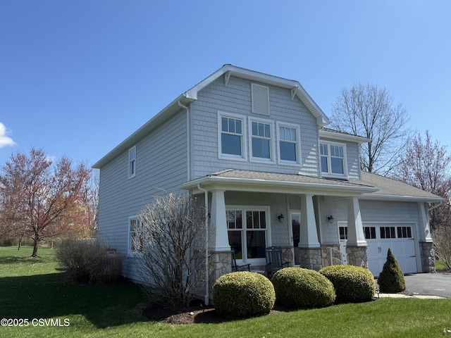 craftsman-style home with a porch, stone siding, a front lawn, an attached garage, and driveway