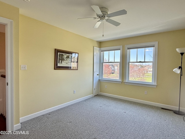 carpeted empty room featuring baseboards and a ceiling fan