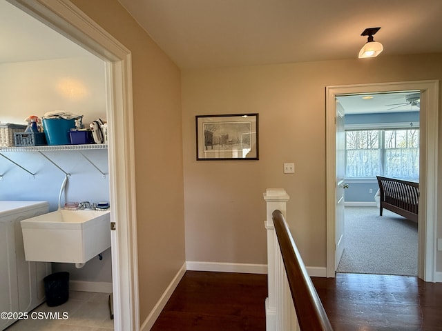 hall with washer / dryer, baseboards, an upstairs landing, and wood finished floors