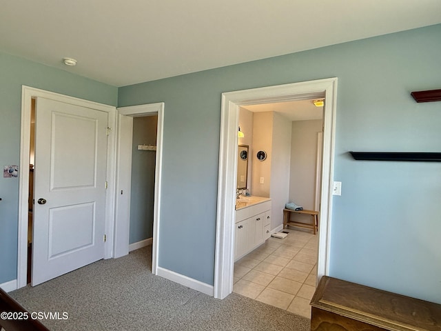 interior space with light carpet, baseboards, a sink, and light tile patterned flooring