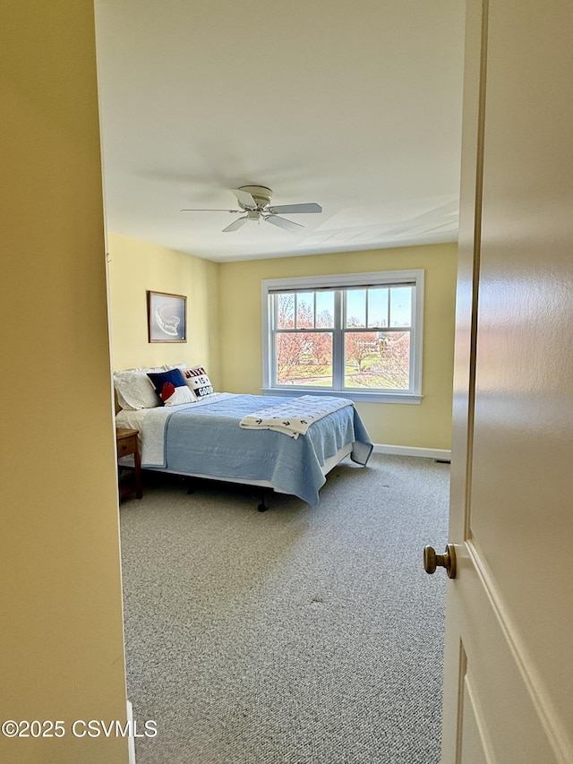 carpeted bedroom with ceiling fan and baseboards