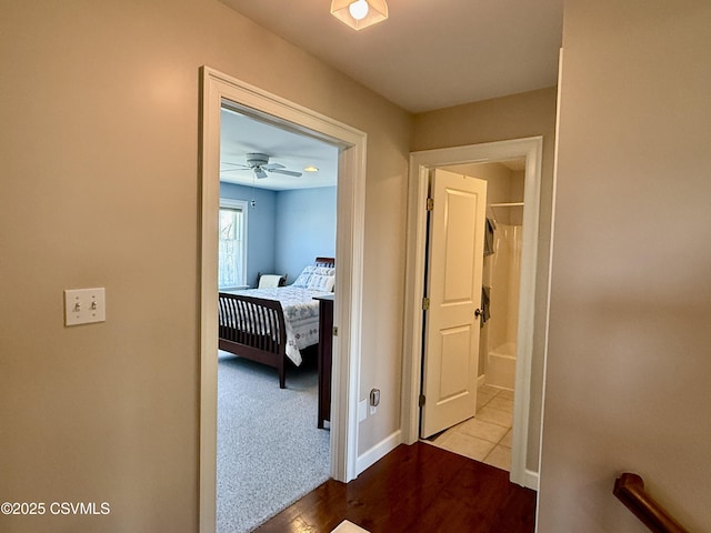 hall with carpet floors, baseboards, and wood finished floors