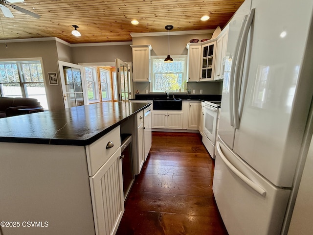 kitchen with a sink, ornamental molding, white appliances, dark countertops, and wooden ceiling