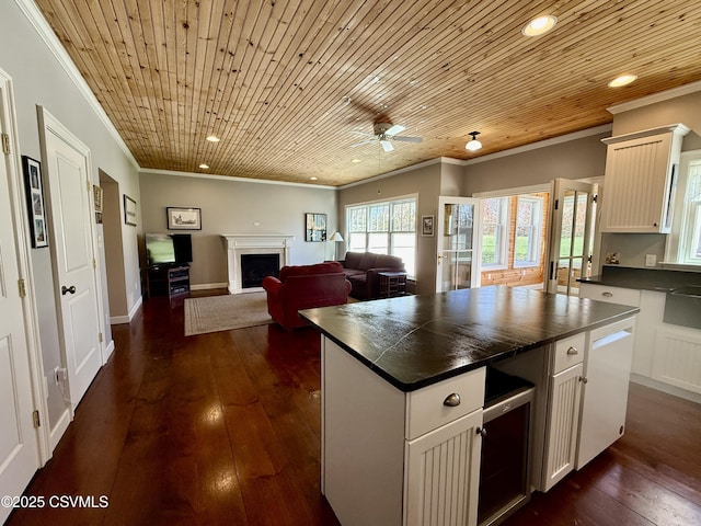 kitchen with dishwasher, ornamental molding, dark countertops, a ceiling fan, and a fireplace
