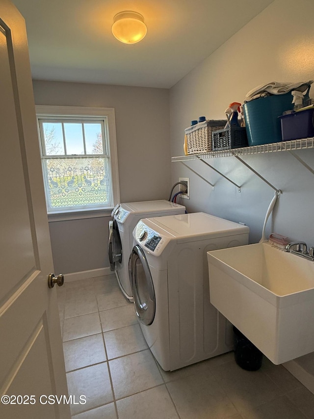 laundry area with light tile patterned floors, baseboards, a sink, laundry area, and independent washer and dryer