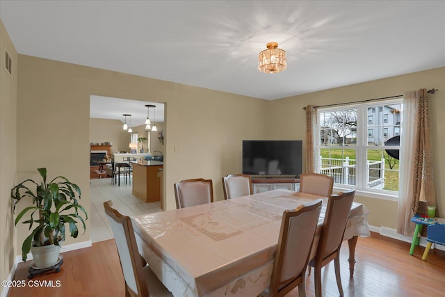 dining space with a chandelier, light wood finished floors, baseboards, and visible vents