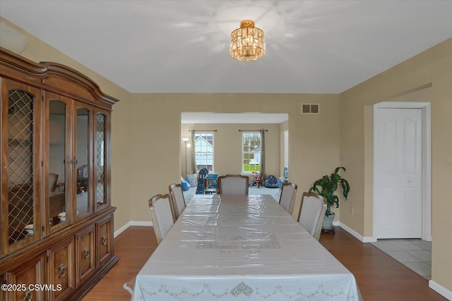dining room featuring visible vents, baseboards, an inviting chandelier, and wood finished floors