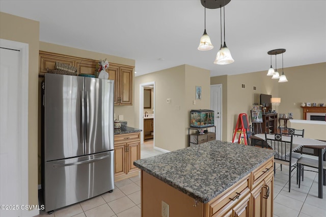 kitchen with hanging light fixtures, freestanding refrigerator, a kitchen island, and light tile patterned flooring