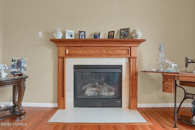 interior details with a fireplace with flush hearth, baseboards, and wood finished floors
