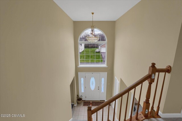 entrance foyer with baseboards, an inviting chandelier, a high ceiling, stairs, and tile patterned floors