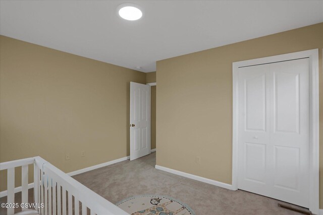 unfurnished bedroom featuring a closet, light colored carpet, baseboards, and visible vents