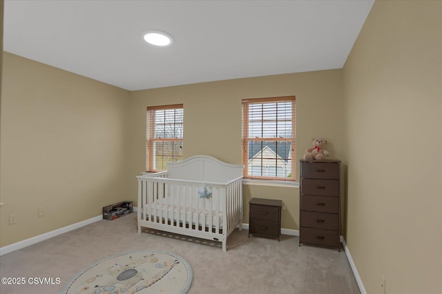 bedroom with a crib, carpet, and baseboards