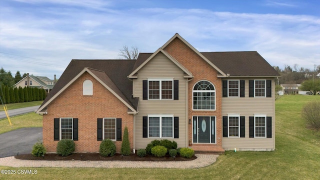 colonial house featuring a front yard and brick siding