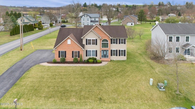 view of front of property with driveway, a front yard, a residential view, and brick siding