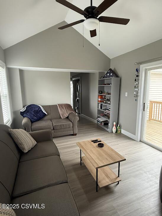 living room with ceiling fan, light wood-type flooring, high vaulted ceiling, and baseboards
