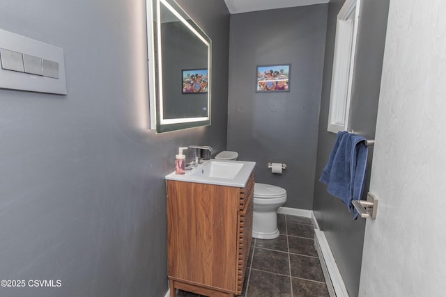 half bathroom featuring toilet, tile patterned floors, vanity, and baseboards