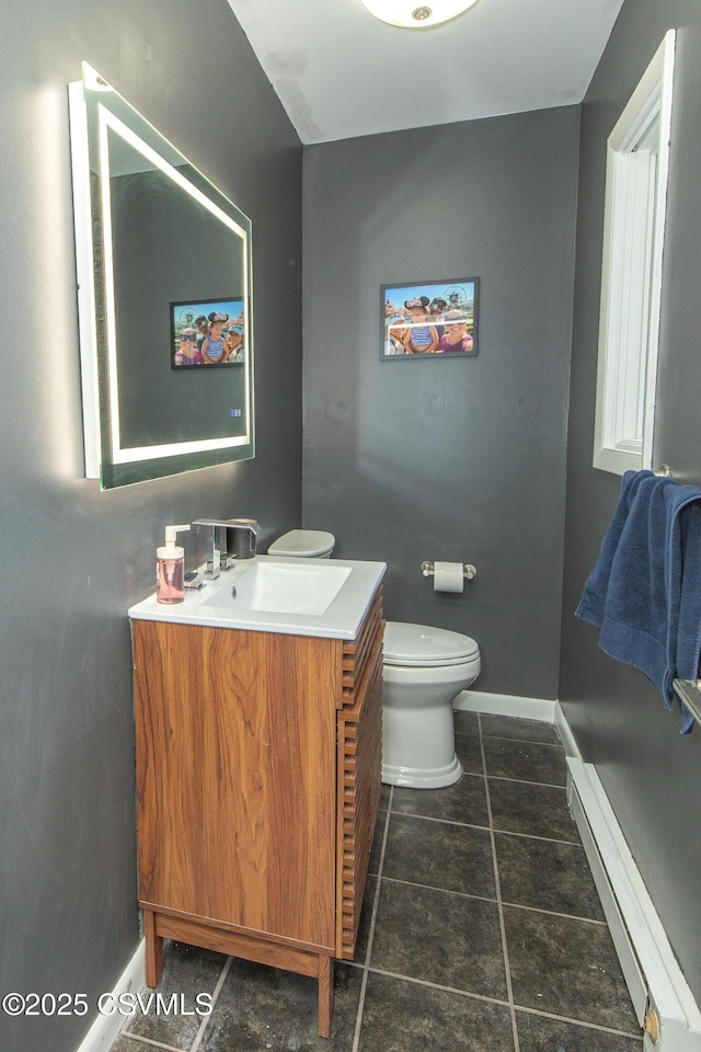 half bath featuring vanity, baseboards, baseboard heating, and toilet