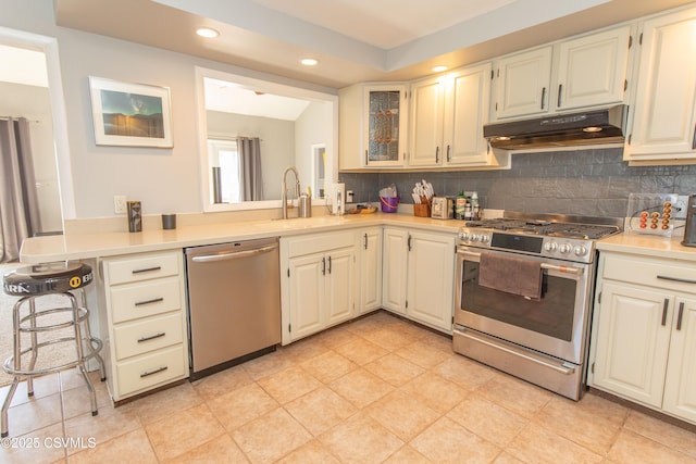 kitchen featuring a sink, light countertops, under cabinet range hood, recessed lighting, and stainless steel appliances