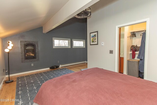 bedroom with a fireplace, lofted ceiling, baseboard heating, and wood finished floors