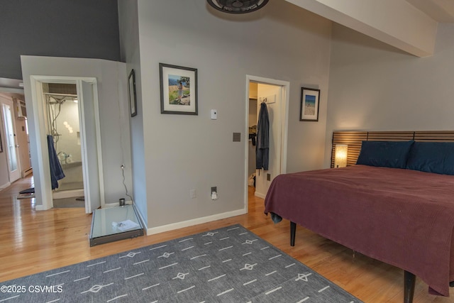 bedroom featuring baseboards, a walk in closet, and wood finished floors