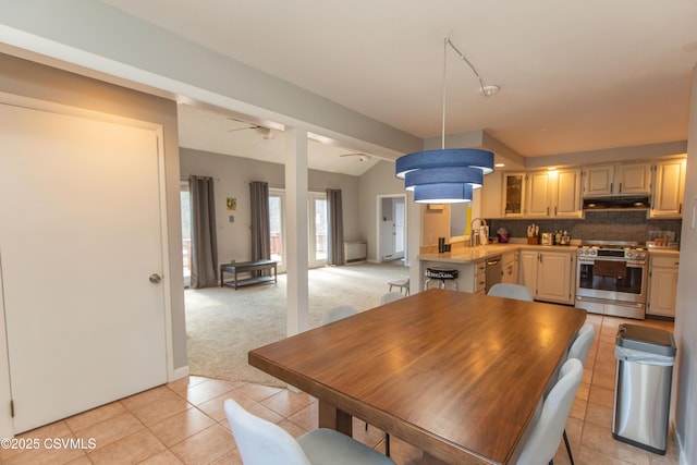 dining space featuring light carpet, light tile patterned floors, and lofted ceiling