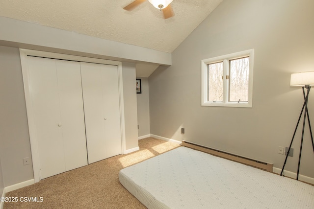 unfurnished bedroom featuring a closet, a textured ceiling, carpet floors, lofted ceiling, and a baseboard radiator