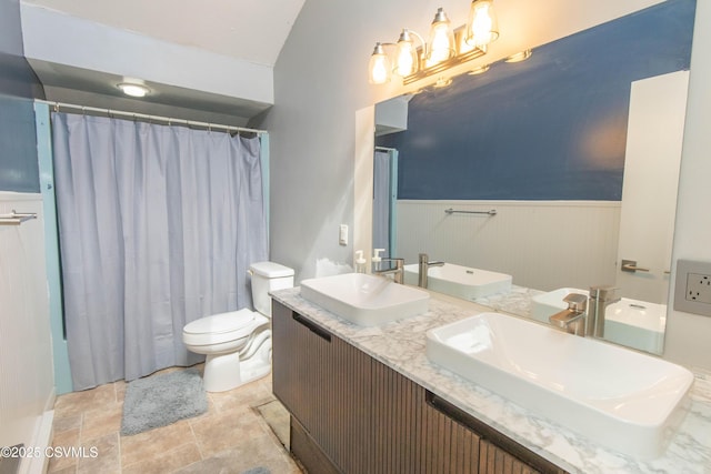 bathroom featuring toilet, a sink, and wainscoting
