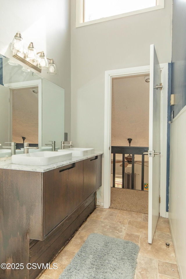 bathroom with stone finish floor, vanity, and a high ceiling