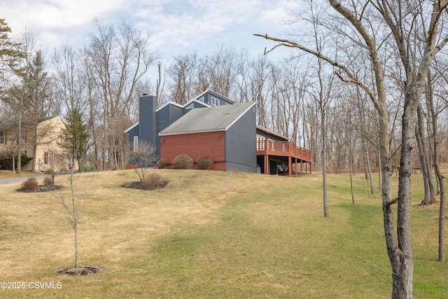 view of property exterior with a chimney, a wooden deck, and a lawn