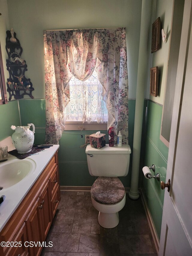 half bathroom with toilet, vanity, and baseboards