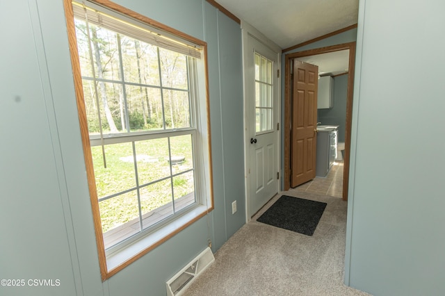 doorway to outside with carpet flooring, visible vents, and vaulted ceiling