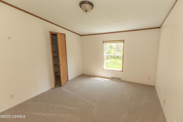 unfurnished room with carpet floors, visible vents, and ornamental molding
