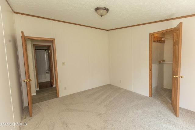 unfurnished bedroom with carpet floors, ornamental molding, a textured ceiling, and a spacious closet