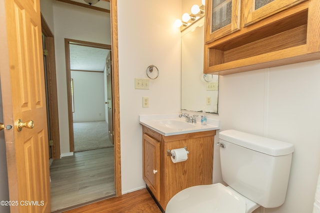 half bathroom featuring vanity, wood finished floors, and toilet