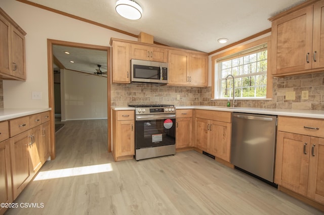 kitchen with vaulted ceiling, appliances with stainless steel finishes, light wood finished floors, and tasteful backsplash
