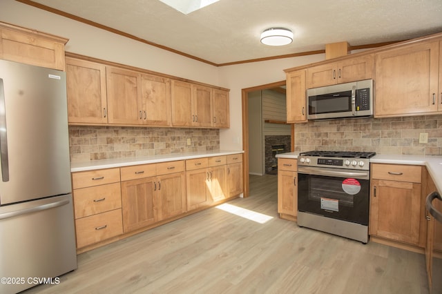 kitchen with appliances with stainless steel finishes, tasteful backsplash, light countertops, light wood-type flooring, and ornamental molding