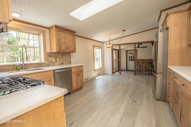 kitchen featuring appliances with stainless steel finishes, a sink, light countertops, backsplash, and ornamental molding
