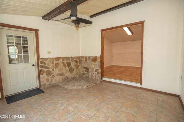 unfurnished room with wooden walls, beam ceiling, a ceiling fan, stone finish flooring, and wood ceiling