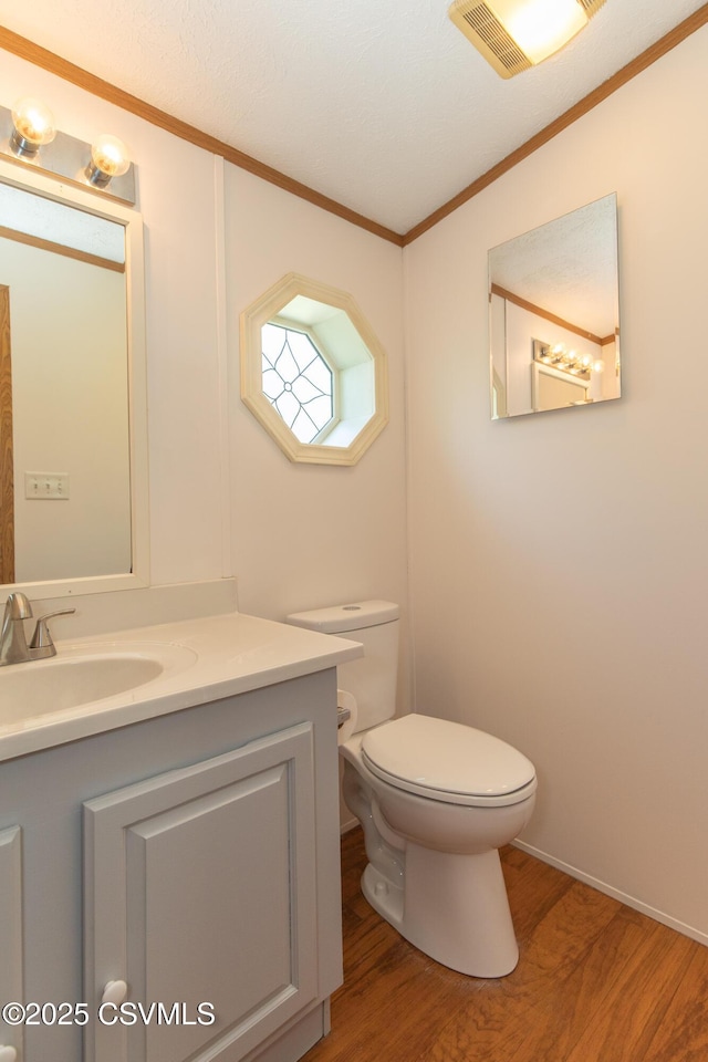 bathroom featuring vanity, toilet, wood finished floors, lofted ceiling, and ornamental molding