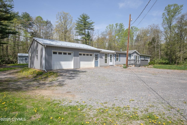 single story home with board and batten siding, driveway, and metal roof
