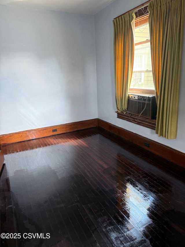 spare room featuring hardwood / wood-style flooring, cooling unit, and baseboards