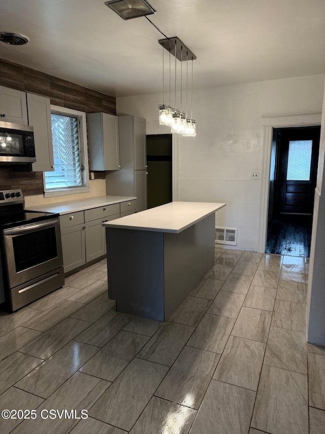 kitchen with gray cabinets, a center island, visible vents, light countertops, and appliances with stainless steel finishes