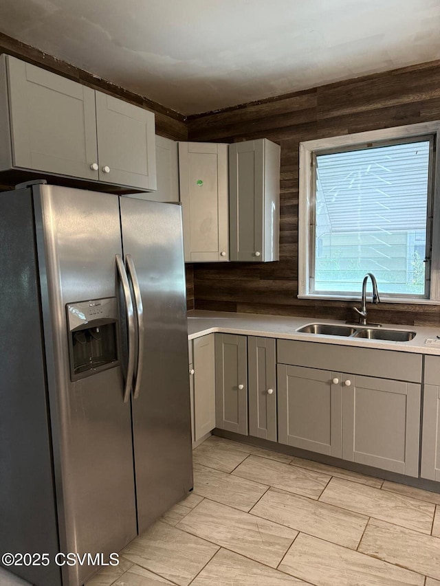 kitchen with a sink, light countertops, stainless steel fridge, and gray cabinets