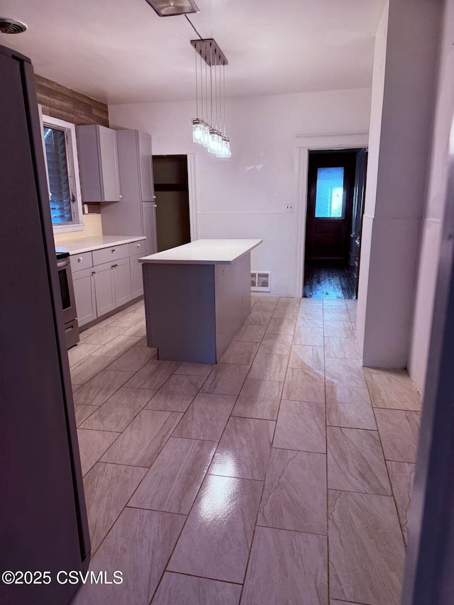 kitchen with a center island, appliances with stainless steel finishes, light countertops, and marble finish floor
