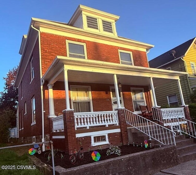 american foursquare style home featuring stairway, a porch, and brick siding
