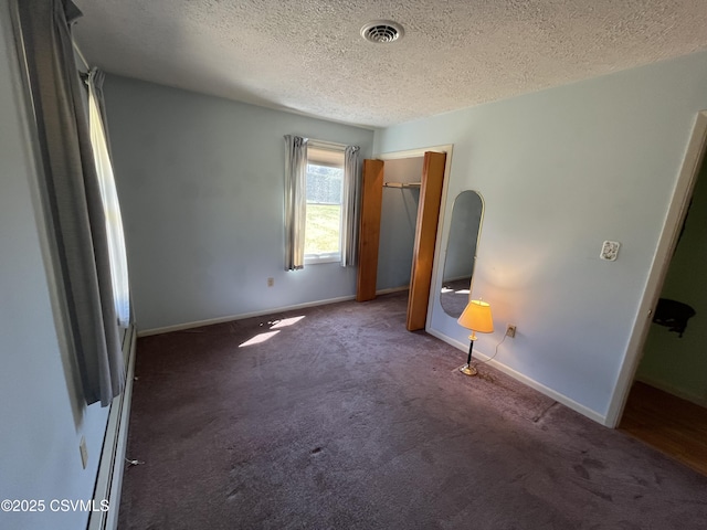 unfurnished bedroom with carpet floors, a textured ceiling, visible vents, and baseboards