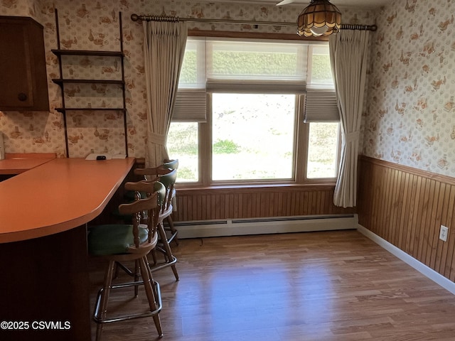 dining area with wallpapered walls, wood finished floors, and a healthy amount of sunlight