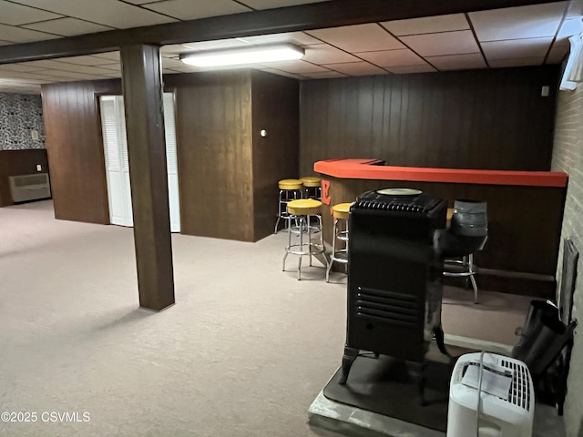 game room with wood walls, carpet floors, a dry bar, and a drop ceiling