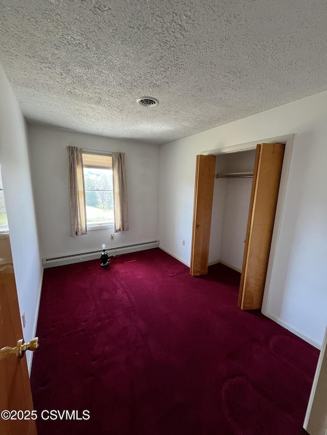 unfurnished bedroom featuring a baseboard radiator, a textured ceiling, a closet, carpet floors, and visible vents