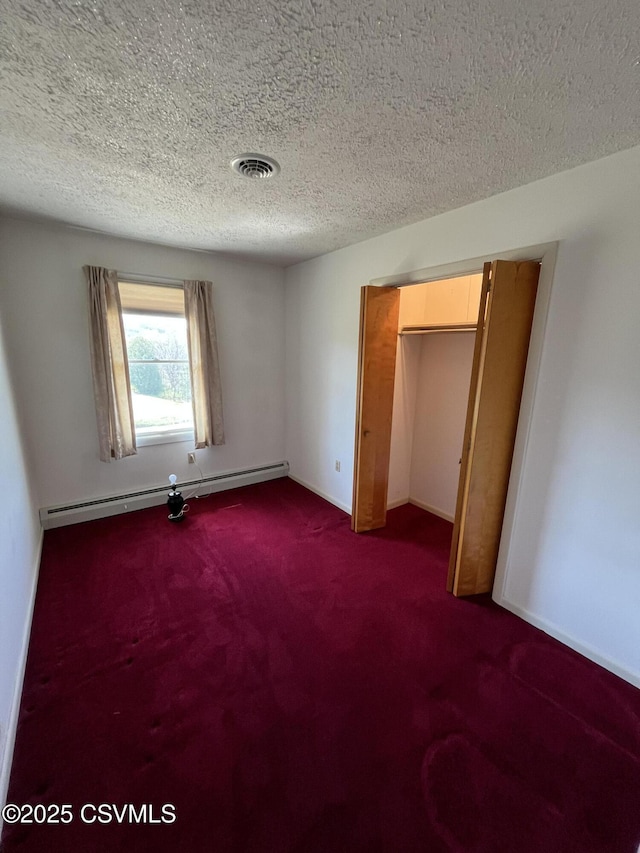 unfurnished bedroom featuring a textured ceiling, dark colored carpet, visible vents, and baseboard heating